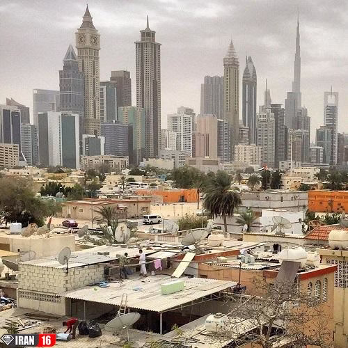 تصویری از برج های بلند و شیک شهر دبی در کنار محله های فقیر را مشاهده می کنید.